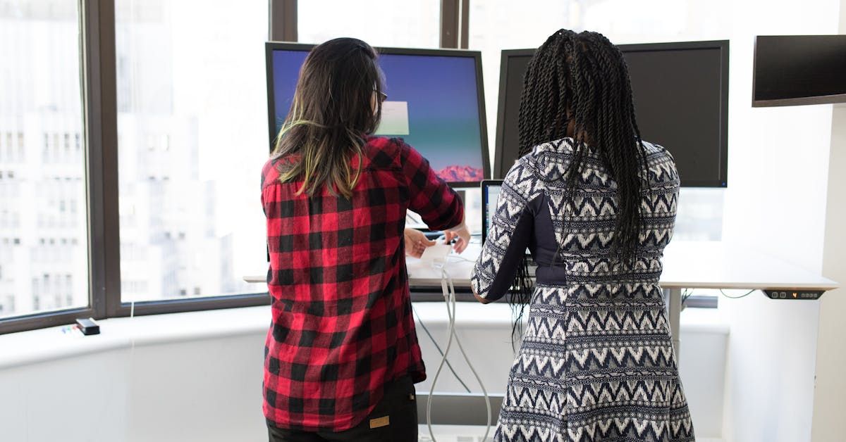 Person at standing desk with dual monitors in modern workspace