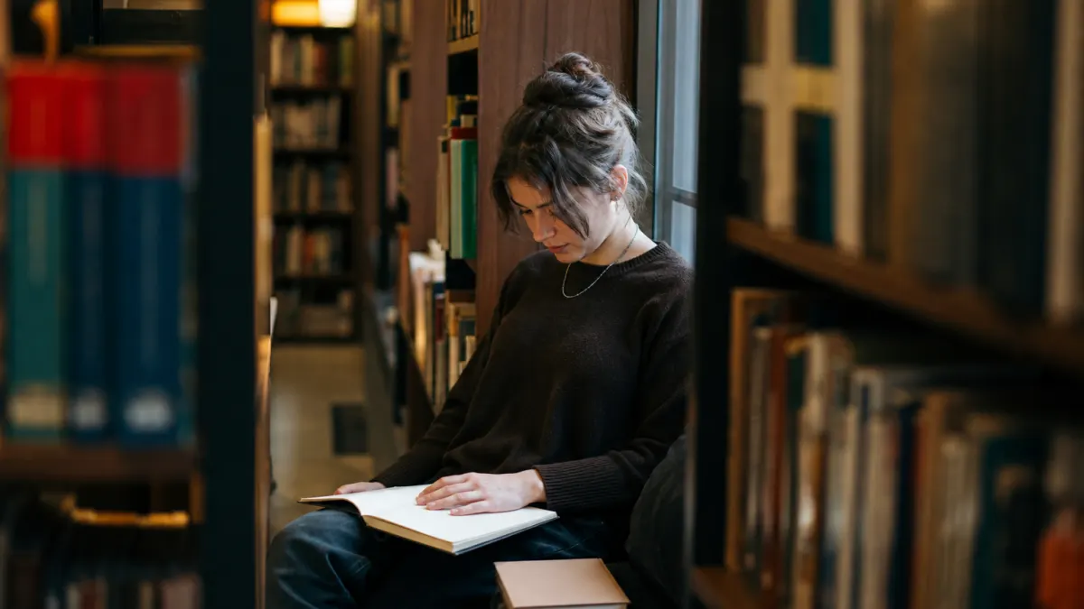 Library reader pauses over notes while considering can professors detect ChatGPT policy questions.