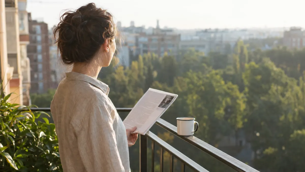 Person holding printed pages up to window light examining text for hidden ChatGPT watermark markers